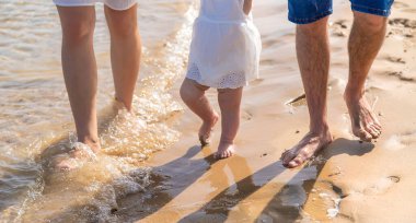 Anne ve baba kumsal boyunca yürüyorlar. Seçici odaklanma. Çocuk.