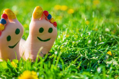 Çimlerin üzerinde çocuk ayakları bir gülümseme çiziyor. Seçici odaklanma. Çocuk.