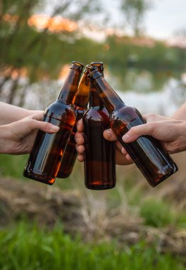 Doğadaki gençlerin elinde bira şişeleri. Seçici odaklanma. Doğa.