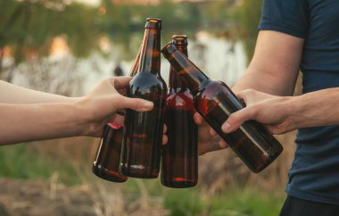 Doğadaki gençlerin elinde bira şişeleri. Seçici odaklanma. Doğa.