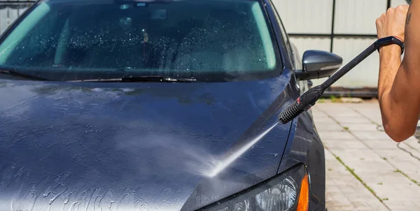 A man washes his car on the street. Selective focus. Nature.