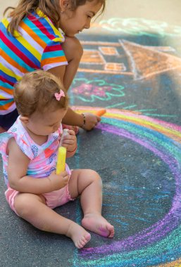 Çocuk asfalta tebeşirle bir ev ve gökkuşağı çizer. Seçici odaklanma. Çocuklar.