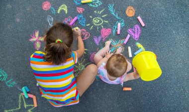 Çocuk asfalta tebeşirle çizer. Seçici odaklanma. Çocuklar.