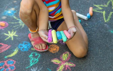 Çocuk asfalta tebeşirle çizer. Seçici odaklanma. Çocuklar.