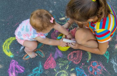 Çocuk asfalta tebeşirle çizer. Seçici odaklanma. Çocuklar.