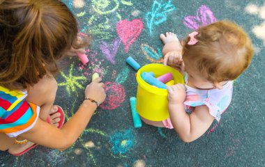 Çocuk asfalta tebeşirle çizer. Seçici odaklanma. Çocuklar.