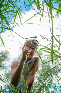Çocuk bir büyüteçten salyangoza bakıyor. Seçici odaklanma. Doğa.