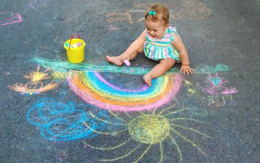 Bebek kaldırıma tebeşirle gökkuşağı çiziyor. Seçici odaklanma. Doğa.