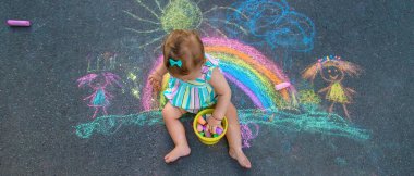 Bebek kaldırıma tebeşirle gökkuşağı çiziyor. Seçici odaklanma. Doğa.