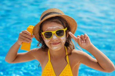 Çocuk yüzüne güneş kremi sürüyor. Seçici odaklanma. Çocuk.