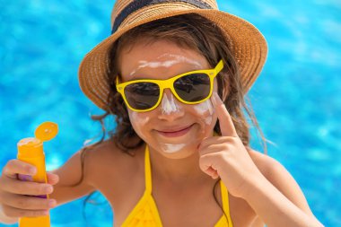 Çocuk yüzüne güneş kremi sürüyor. Seçici odaklanma. Çocuk.