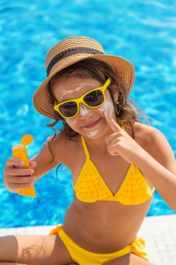 Çocuk yüzüne güneş kremi sürüyor. Seçici odaklanma. Çocuk.