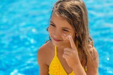 Çocuk yüzüne güneş kremi sürüyor. Seçici odaklanma. Çocuk.