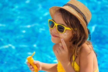 Çocuk yüzüne güneş kremi sürüyor. Seçici odaklanma. Çocuk.