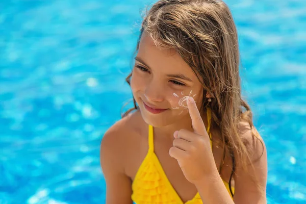 Çocuk yüzüne güneş kremi sürüyor. Seçici odaklanma. Çocuk.