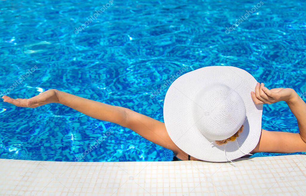 Girl resting near the pool wearing a hat. Selective focus. Woman.