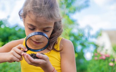 Çocuk bir büyüteçle zemini inceler. Seçici odaklanma. Doğa.