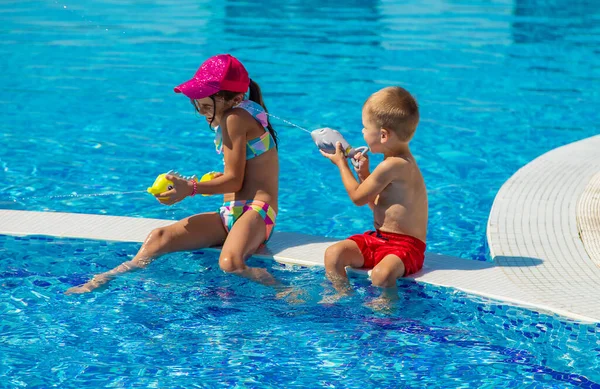 Çocuklar havuzda su tabancalarıyla oynarlar. Seçici odaklanma. Su..