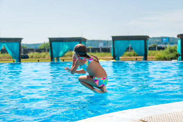 The child jumps dives into the pool. Selective focus. Kid.