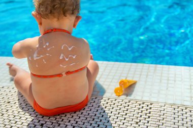 Çocuğun arkasında güneş kremi var. Seçici odaklanma. Çocuk.