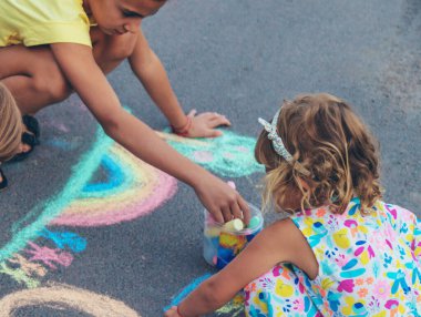 Çocuklar asfalta tebeşirle çizer. Seçici odaklanma. çocuk.