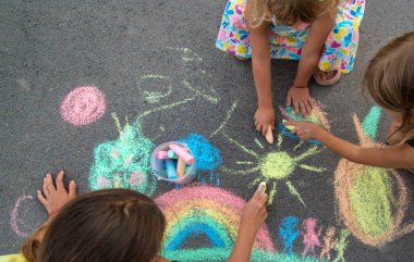 Çocuklar asfalta tebeşirle çizer. Seçici odaklanma. çocuk.