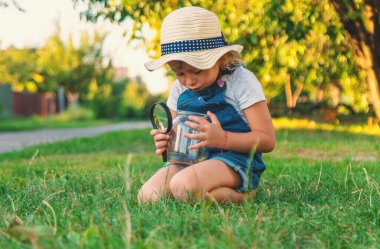 Bir çocuk doğadaki büyüteçten bakar. Seçici odaklanma. Çocuk,
