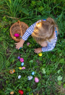 Bir çocuk çimenlerde paskalya yumurtası topluyor. Seçici odaklanma. Çocuk.
