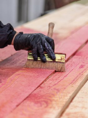 Bir adam tahtaya kırmızı bir antiseptik veriyor. Seçici odaklanma. Doğa.