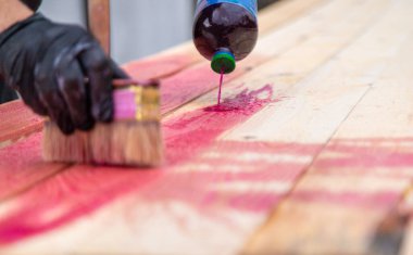 Bir adam tahtaya kırmızı bir antiseptik veriyor. Seçici odaklanma. Doğa.