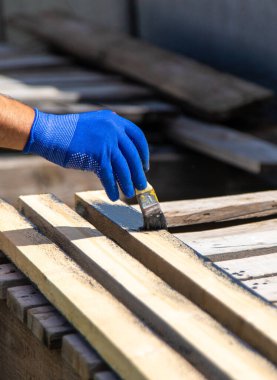 Bir adam bir tahtayı boyayla boyuyor. Seçici odaklanma. Doğa.