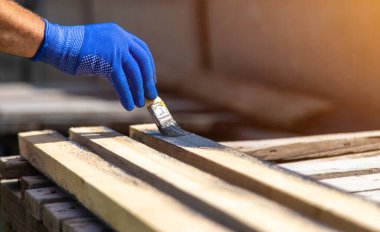 Bir adam bir tahtayı boyayla boyuyor. Seçici odaklanma. Doğa.