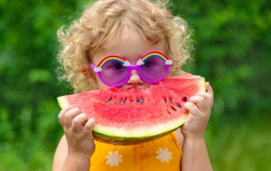 A child eats watermelon in the park. Selective focus. Kid.