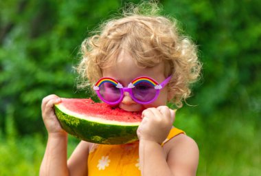 A child eats watermelon in the park. Selective focus. Kid.