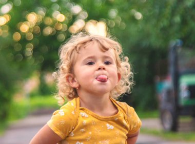 Çocuk sokak portresi üzerinde dilini dışarı çıkarıyor. Seçici odaklanma. Çocuk.