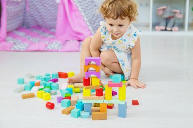 The child plays in the children's room with a wooden constructor. Selective focus. Kid.