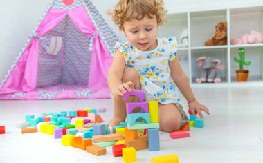 The child plays in the children's room with a wooden constructor. Selective focus. Kid.
