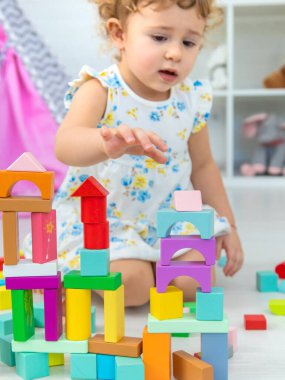 The child plays in the children's room with a wooden constructor. Selective focus. Kid.