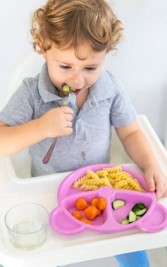 Çocuk makarna ve sebze yiyor. Seçici odaklanma. Çocuk.