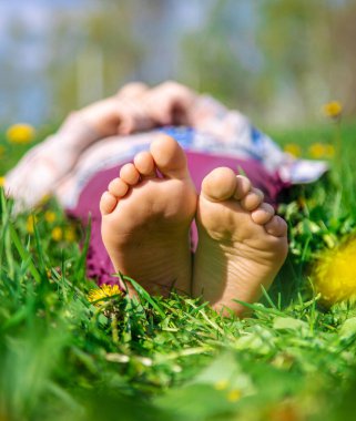 Bahar karahindiba bahçesindeki çimlerin üzerinde çocuk ayakları. Seçici odaklanma. Doğa.