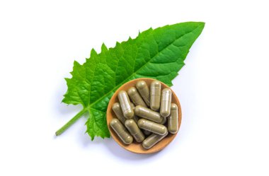 Yeşil yapraklı bitki takviyesi kapsülleri beyaz arka planda izole edilir. Seçici odaklanma. Doğa.