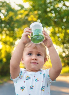 A child is studying a snail in the park. Selective focus. Nature.