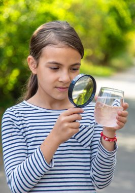 Çocuk bir büyüteçle suyu inceler. Seçici odaklanma. Çocuk.