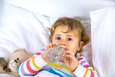 Bir çocuk yataktaki bir şişeden içer. Seçici odaklanma. Çocuk.