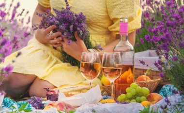 Bir kadın lavanta tarlasında şarap içiyor. Seçici odaklanma. Yiyecek..