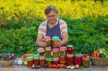 Senior woman preserving vegetables in jars. Selective focus. Food.