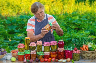 Senior woman preserving vegetables in jars. Selective focus. Food.