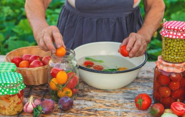 Senior woman preserving vegetables in jars. Selective focus. Food.