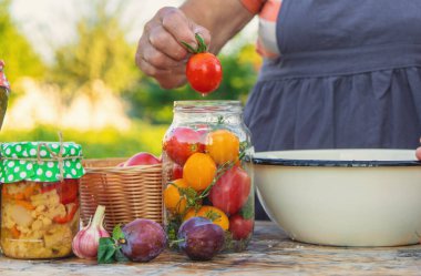 Senior woman preserving vegetables in jars. Selective focus. Food.