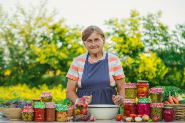 Senior woman preserving vegetables in jars. Selective focus. Food.